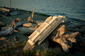 Folded Igni sauna benches resting against driftwood beside the ocean