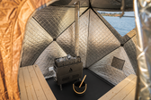 Inside the Igni sauna tent with wood-fired stove, rock basket, bucket and ladle